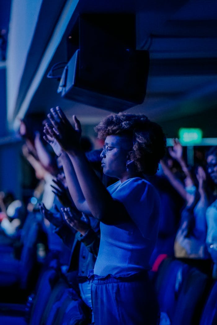 Crowd raising hands during a spiritual event indoors, expressing unity and faith.