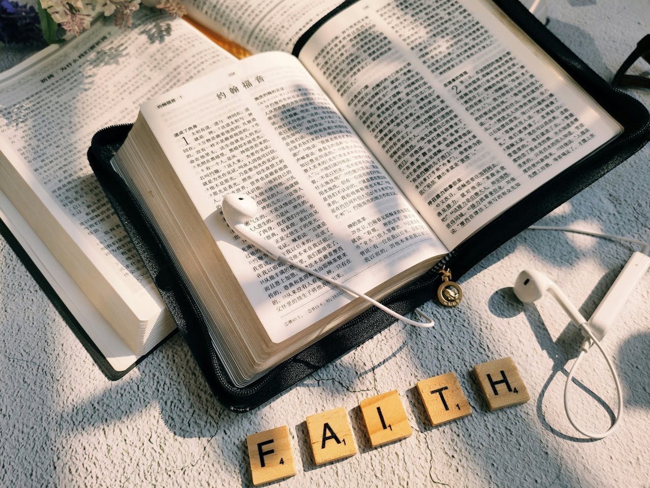 Open Bible with earphones and Scrabble tiles spelling 'FAITH' highlighting spirituality and modernity.