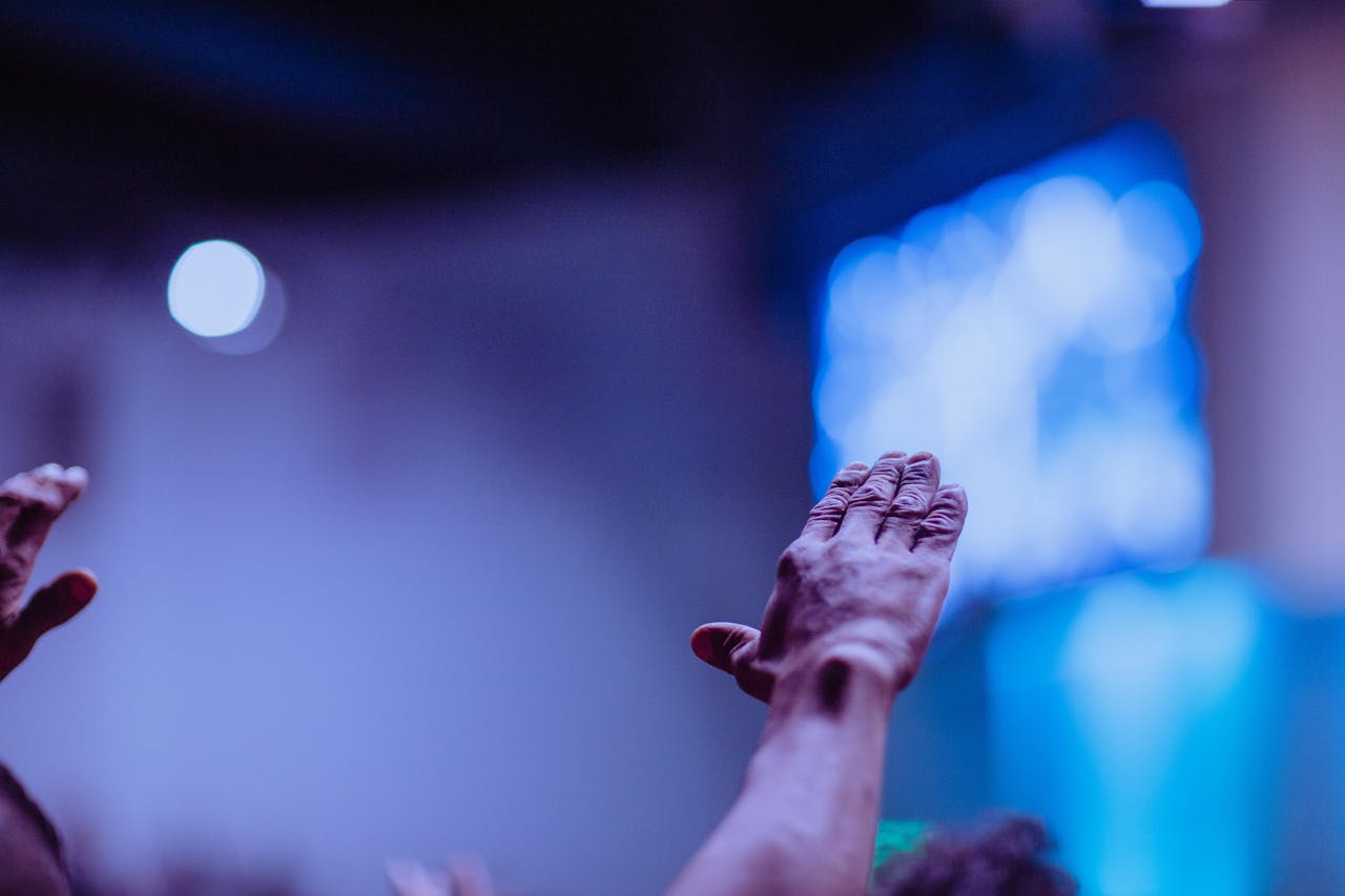 A close-up of hands raised during a church worship service, emphasizing community and praise.